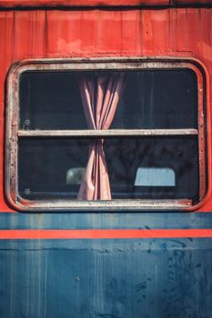 Close-up of an old train window with a pink curtain captured in İstanbul, Türkiye.