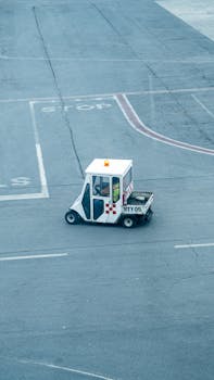 Aerial view of a small airport service vehicle on the tarmac, featuring a white and red checker design.