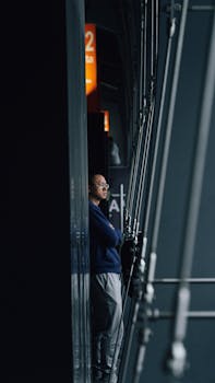 Man with arms crossed waiting by a window in an airport terminal.