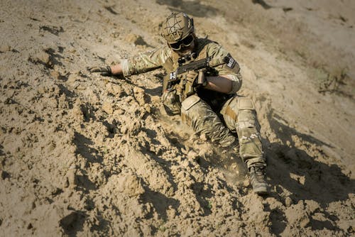 Soldado Descendo A Colina Segurando O Rifle Durante O Dia