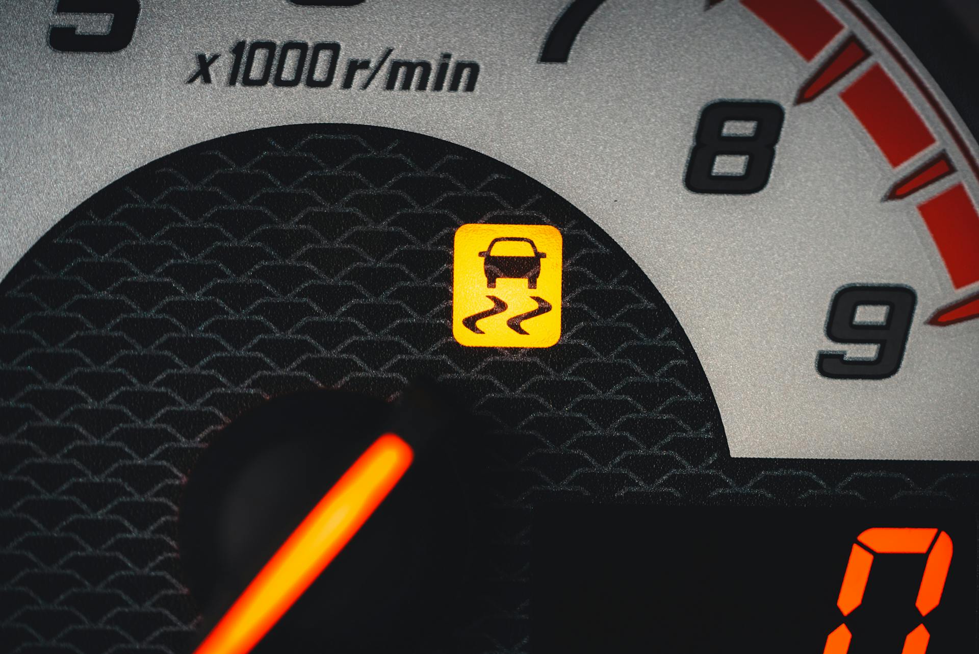 Close-up of a car dashboard showing a yellow traction control warning light.