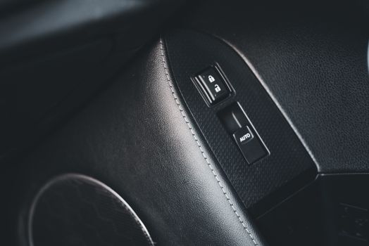 Detailed view of a car interior focusing on lock and auto buttons with leather trim.