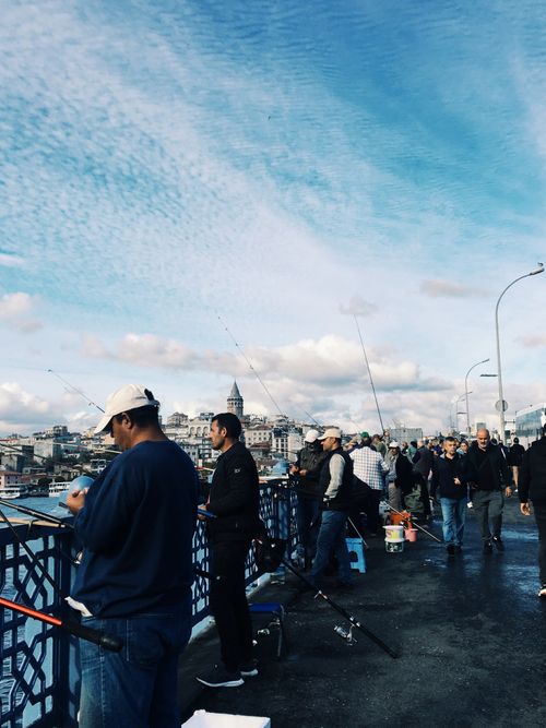 Free People enjoying leisure fishing on the bustling Galata Bridge in Istanbul under a clear blue sky. Stock Photo
