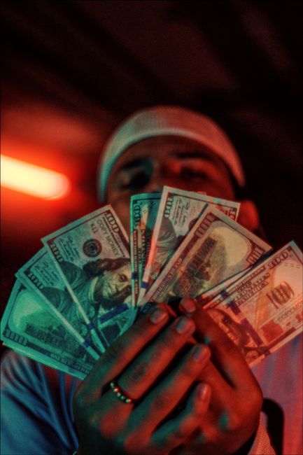 An adult man holds fanned out US dollar bills, showcasing wealth and finance concepts. An adult man holds fanned out US dollar bills, showcasing wealth and finance concepts.