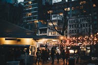 热闹的城市场景中，人们在串灯下享受晚间聚会