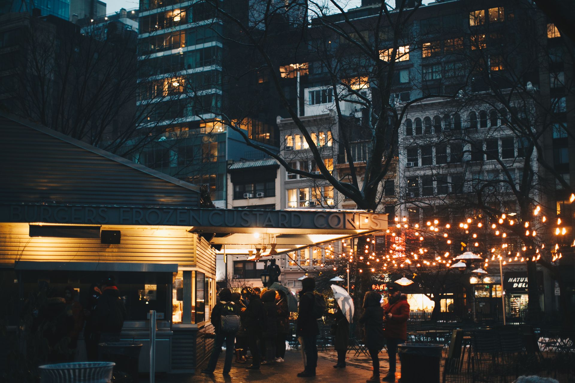Bustling urban scene with people enjoying an evening gathering under string lights.