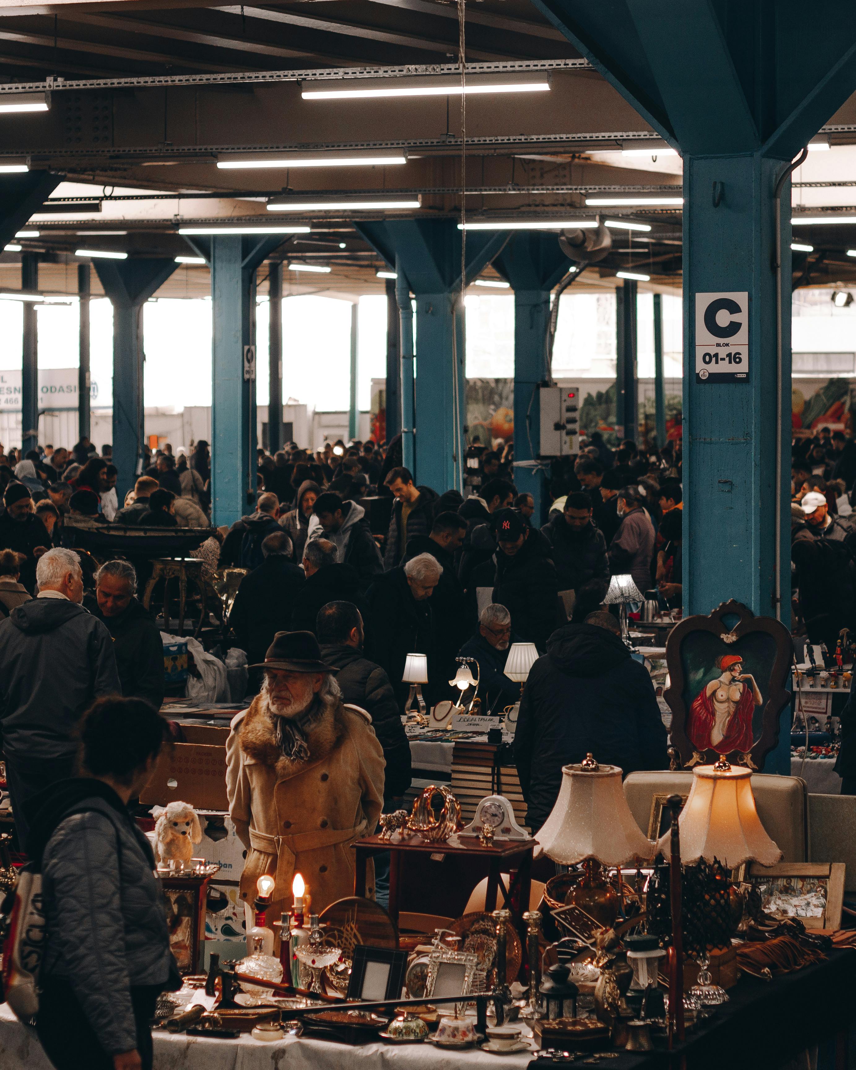 Explore a crowded flea market indoors, featuring vintage decor and diverse crowds.