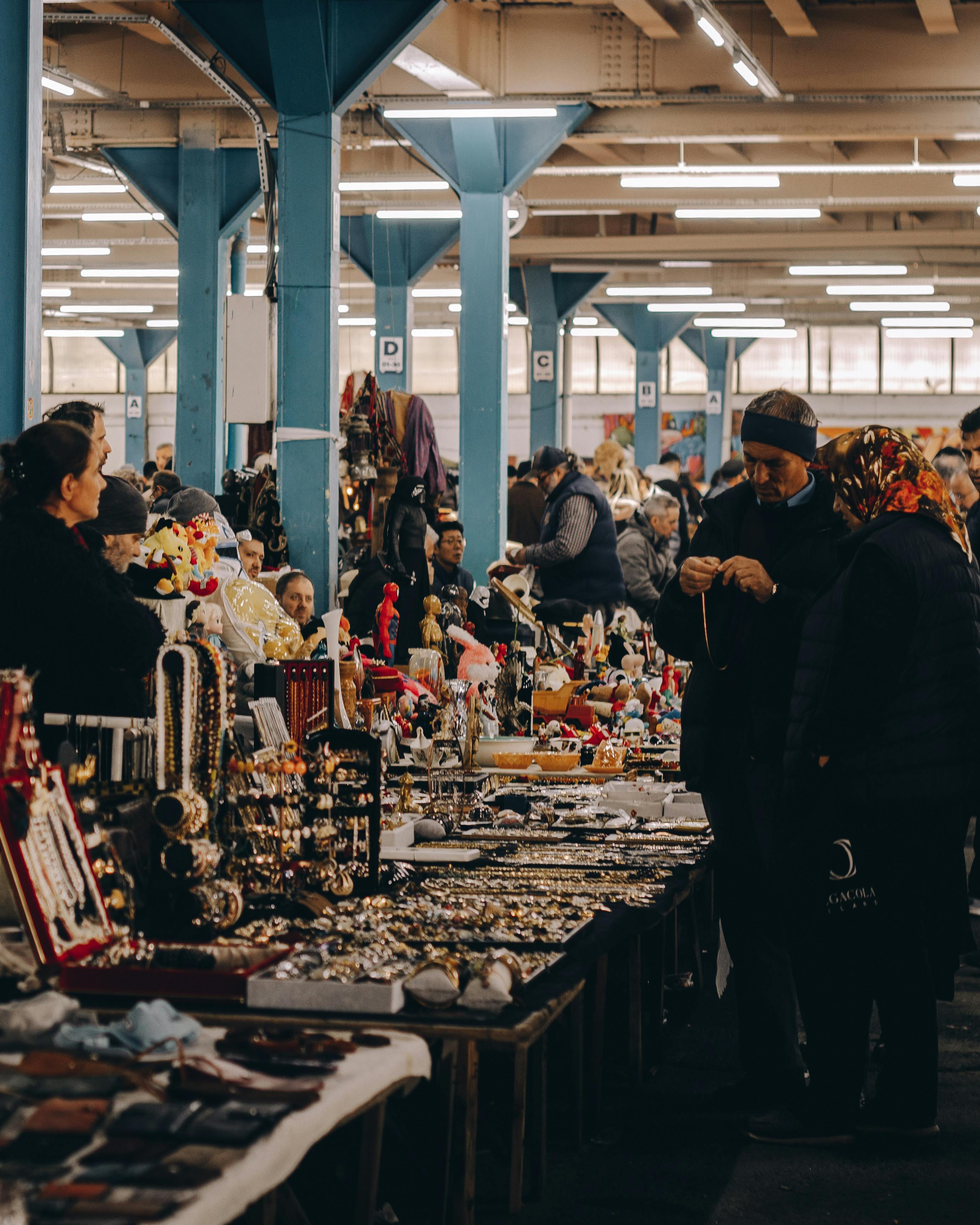 Indoor market scene with diverse stalls bustling with people shopping and trading.