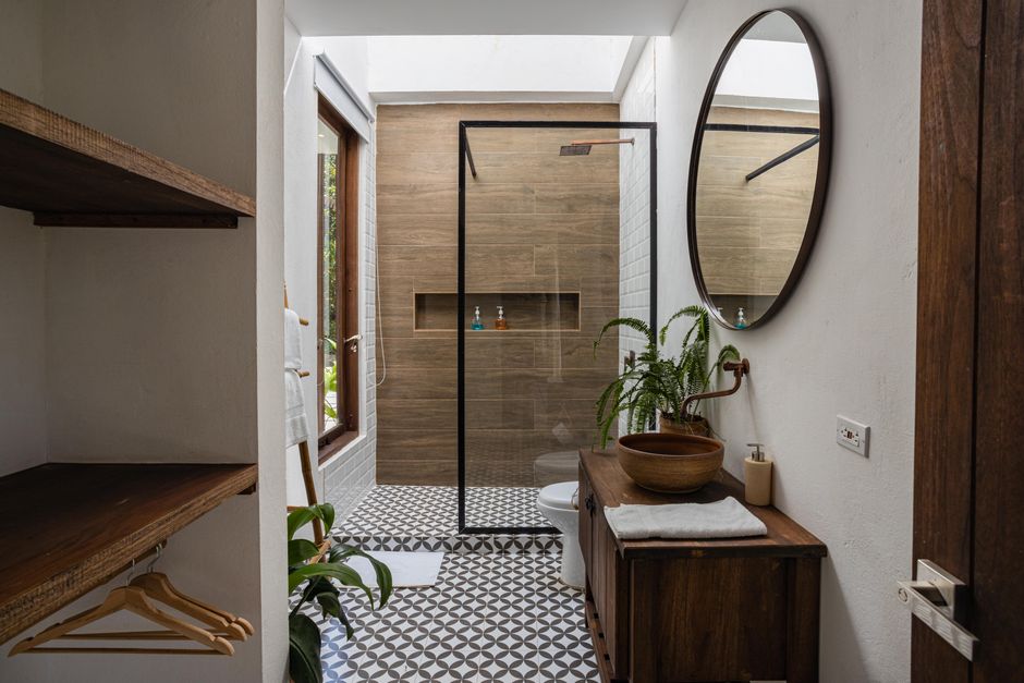 Photo by Gustavo Galeano Maz on Pexels Stylish bathroom interior with a round mirror, wooden accents, and walk-in shower.