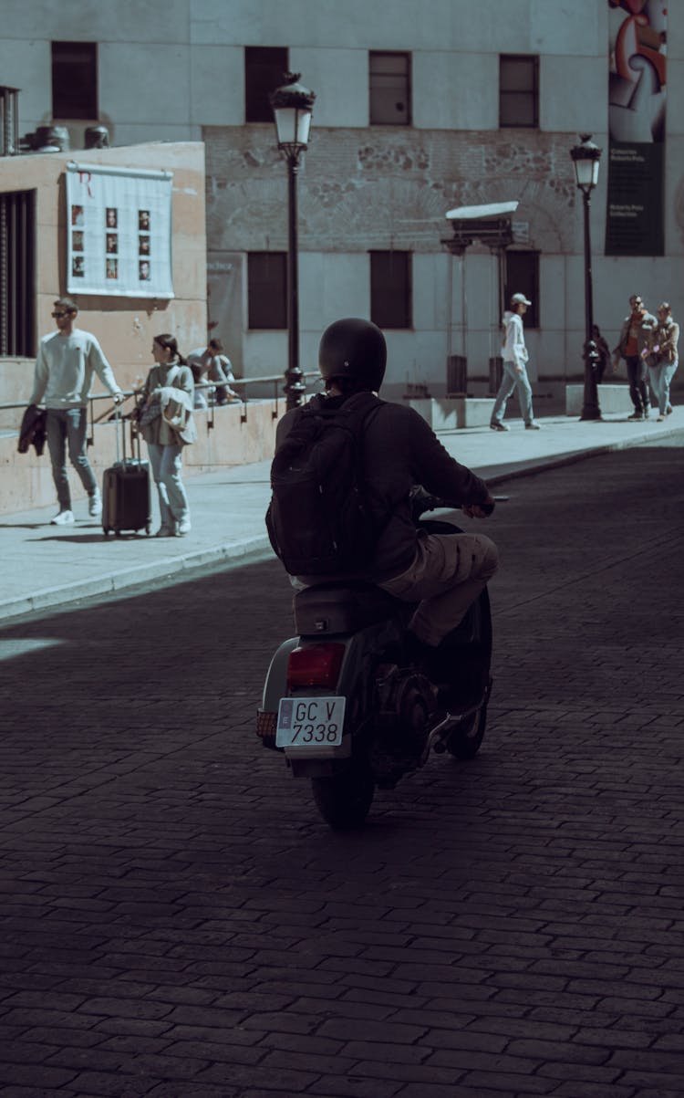 Person Riding Scooter On Street In Shadow