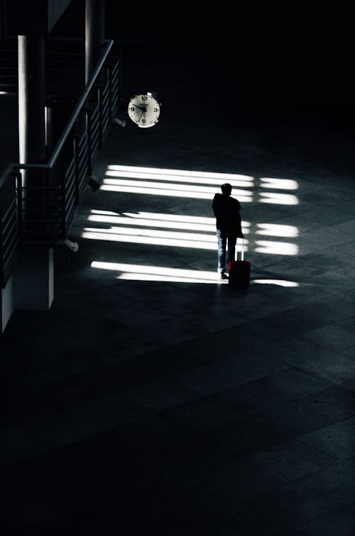 Person with Suitcase Walking near Clock
