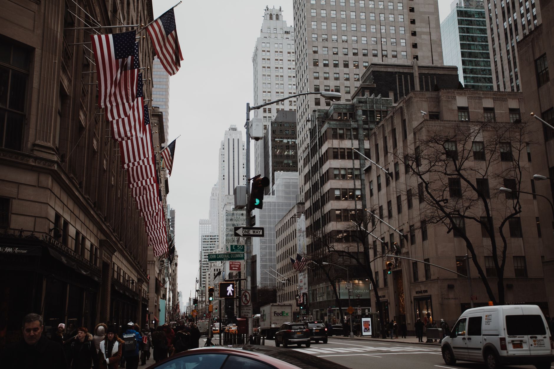 Bustling street scene with skyscrapers, traffic, and American flags in New York City.