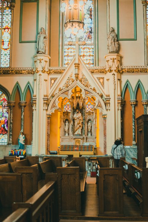 Free Elegant Gothic church interior featuring altar, stained glass windows, and wooden pews. Stock Photo