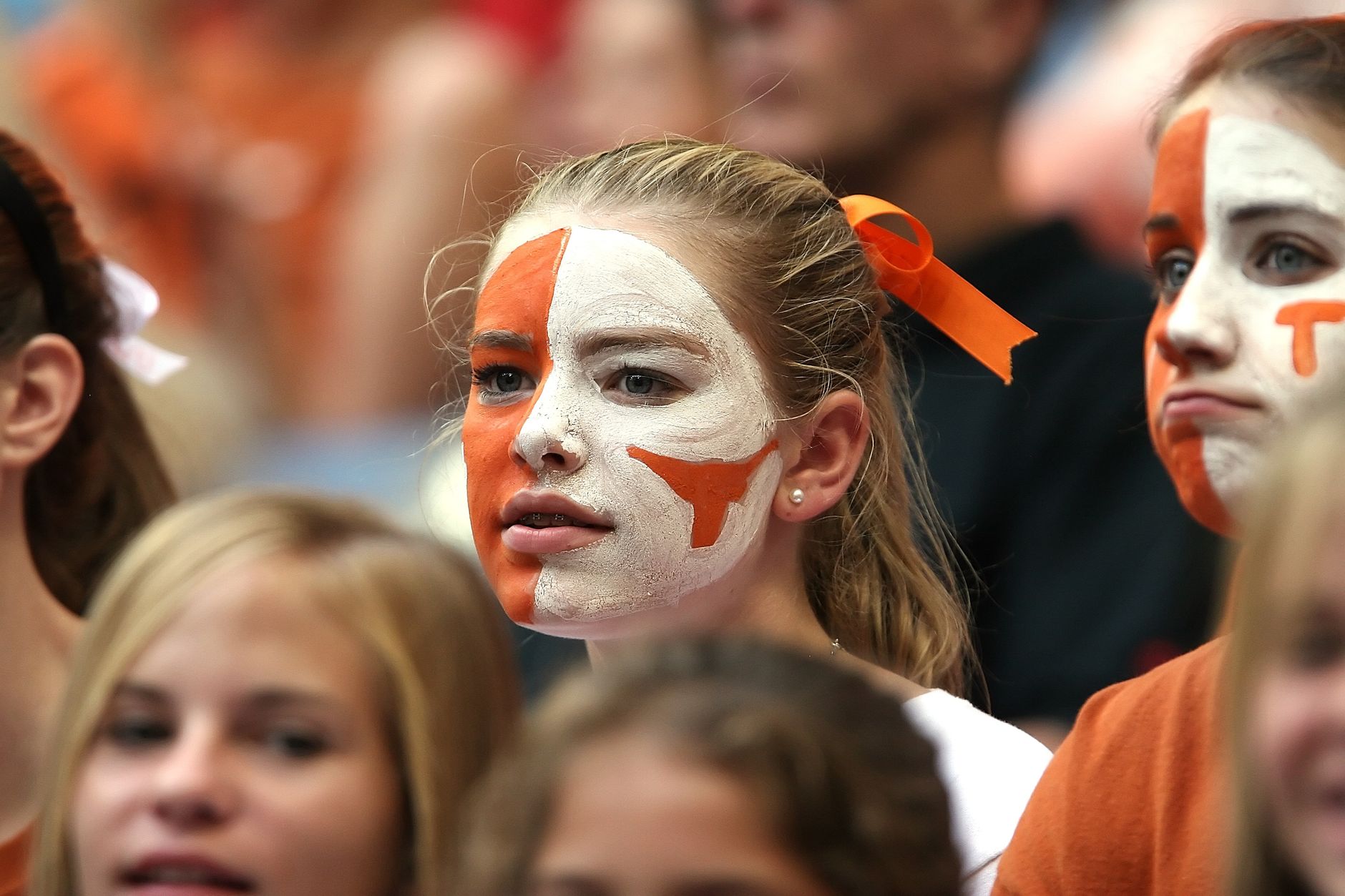 Group of enthusiastic young women with face paint cheering at a sports event.