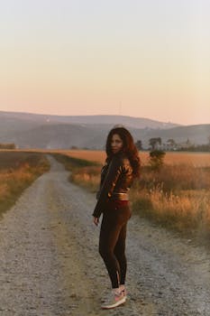 日落时分，一位妇女站在乡间碎石小路上，唤起一片宁静的情绪