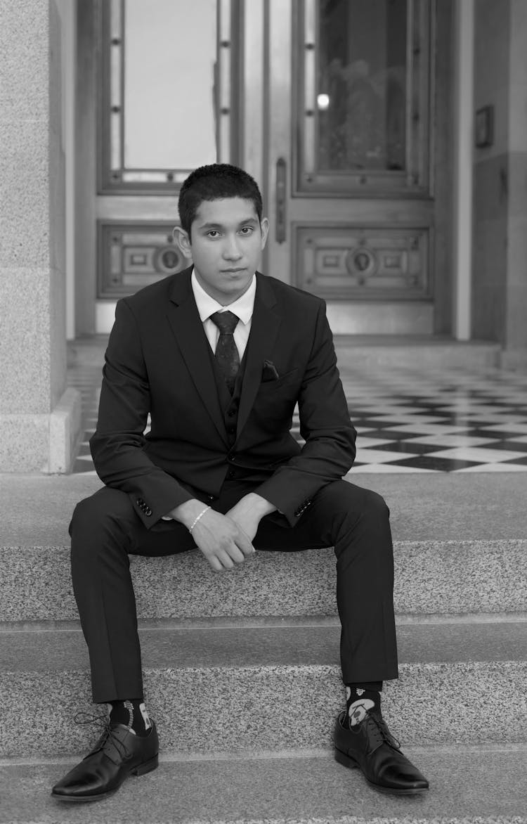 Young Man In Suit Sitting On Steps