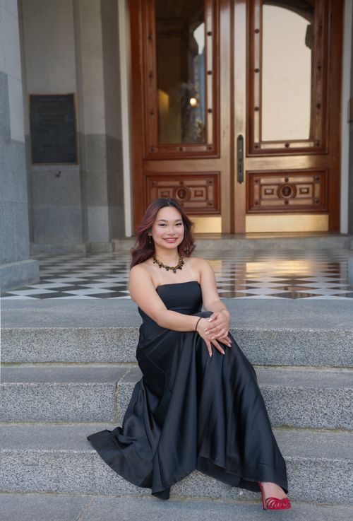 Free Stylish woman in off-shoulder black gown sitting gracefully on steps. Stock Photo