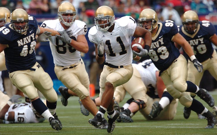 Group Of Male Football Players Running On Field During Day