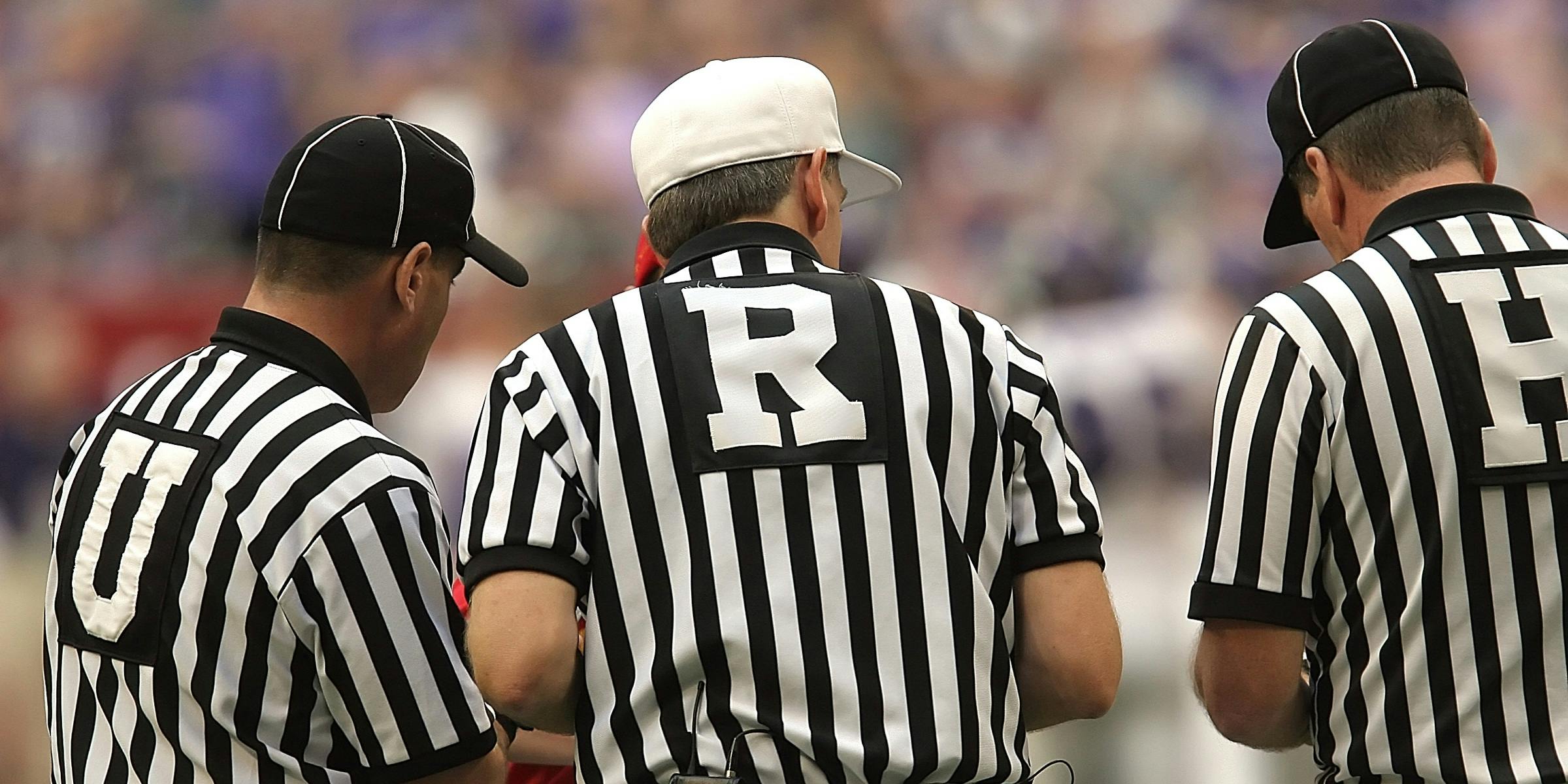 3 referees standing on field