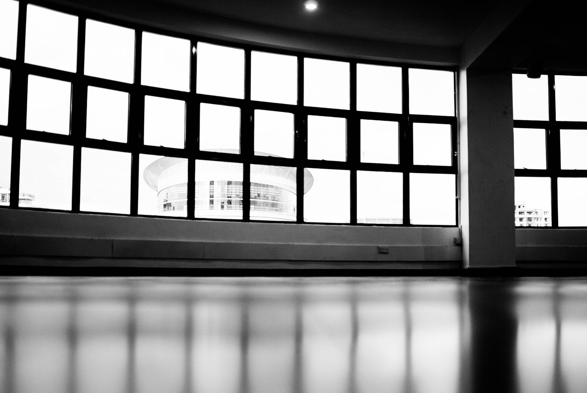 Grayscale interior of a modern office with large windows and skyline view.