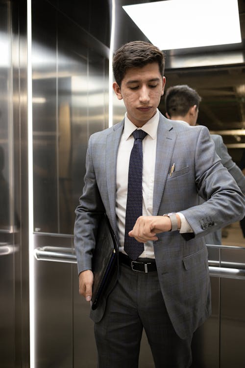 Man in Gray Suit Checking Time in Elevator