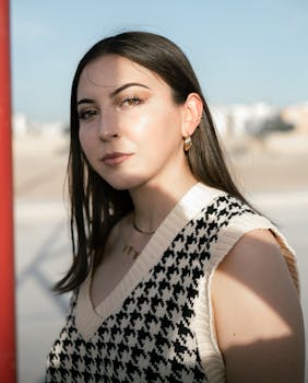 Outdoor portrait of a stylish young woman with gold jewelry in natural sunlight.
