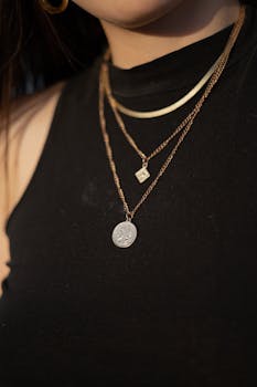 Closeup of a woman wearing a black crop top and layered gold necklaces. Fashion jewelry.