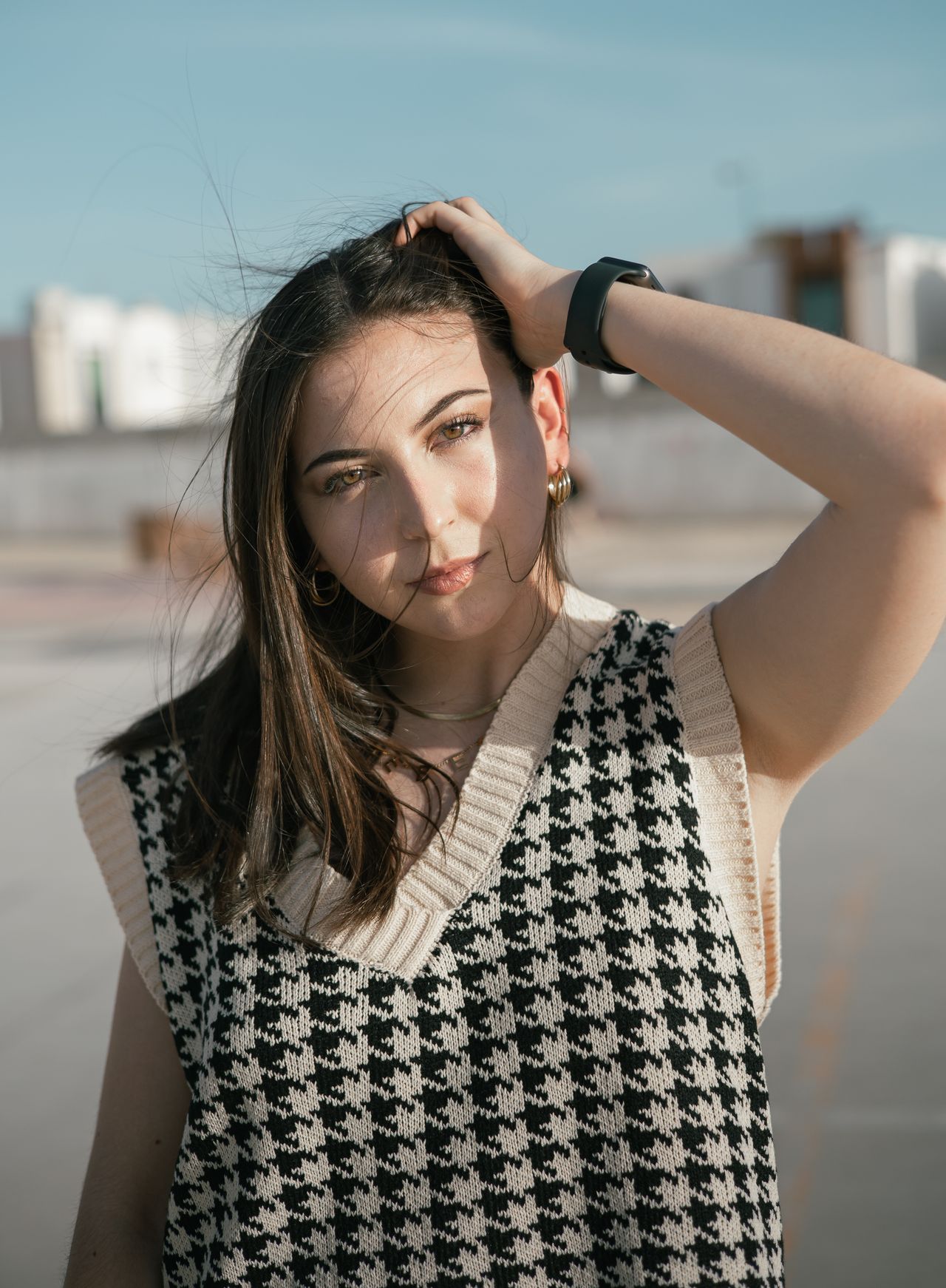 Woman wearing a black and white houndstooth check knit vest with cream trim