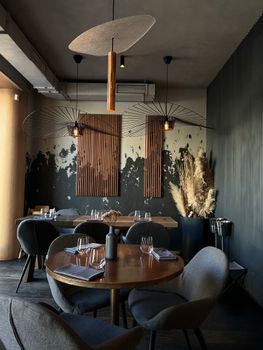 Stylish restaurant with modern decor, featuring round tables, chairs, and creative lighting.