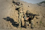 两名士兵身着迷彩，在沙漠环境中进行战术训练