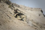 一名士兵身穿战术装备，手持步枪在沙漠环境中展示军事准备