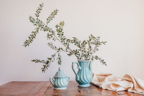 Free A serene still life featuring a cerulean porcelain vase with delicate branches on a wooden table. Stock Photo