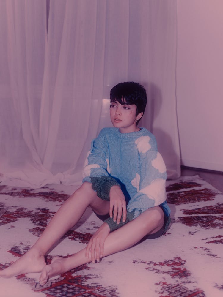 Girl Sitting On A Rug In A Sweater