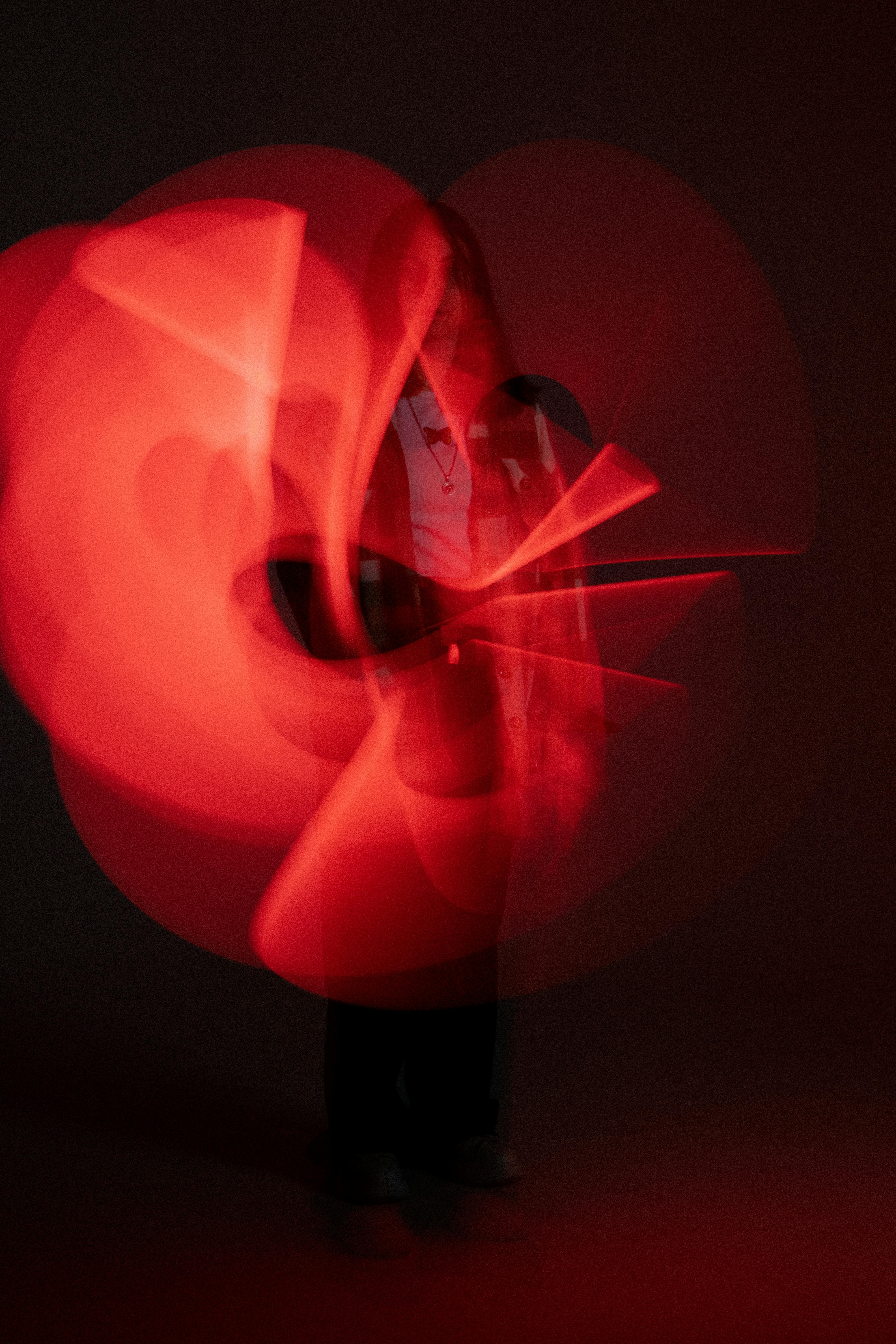 A captivating long exposure of a person with swirling red light patterns in a studio setting.