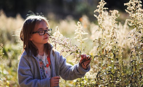 Free Girl Wearing Eyeglasses Smelling Flowers Stock Photo