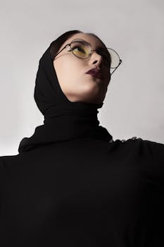 Bold portrait of a woman wearing a hijab and sunglasses, showcasing modern fashion with a dramatic low angle shot.