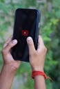 Hands Holding Smartphone with YouTube Logo on Touchscreen
