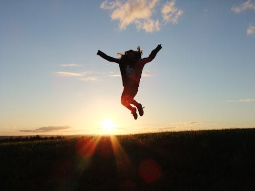 Free Silhouette Photo of a Person Jumping Nearby Green Grass Field during Golden Hour Stock Photo