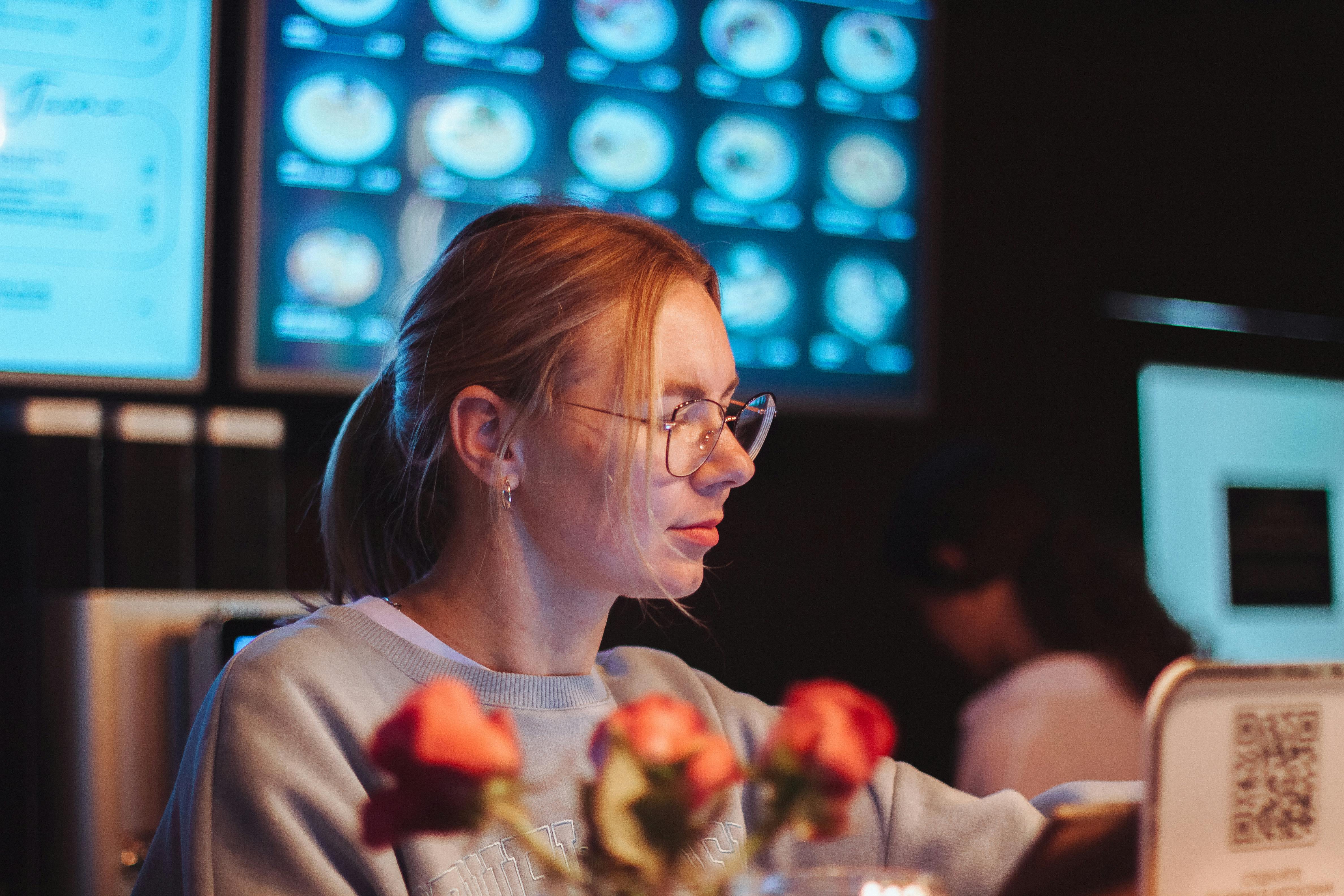 A focused woman working on her laptop in a cozy cafe setting with flowers in the foreground.