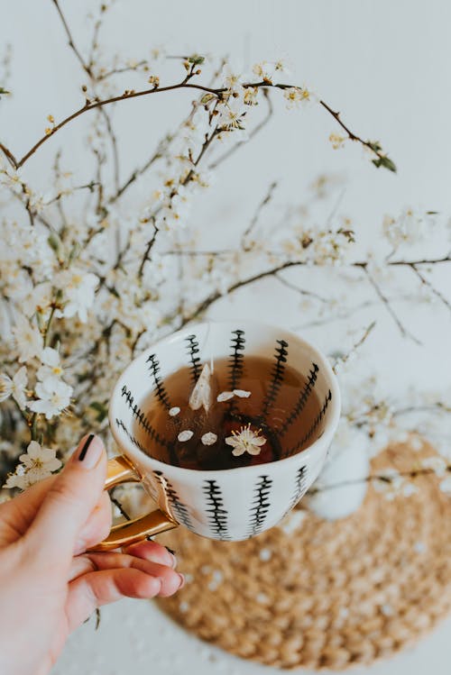 Woman Hand Holding Tea Cup with Petals