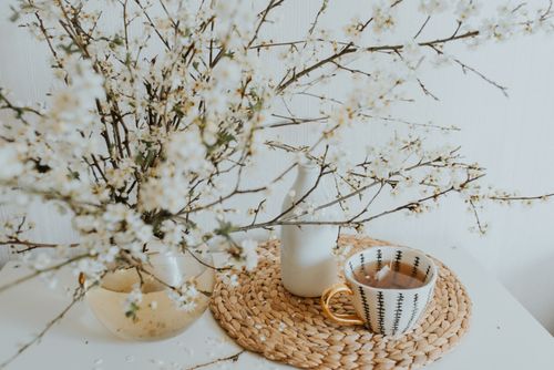 Free A delicate arrangement of blooming branches, vase, and tea cup on a woven mat, exuding spring vibes. Stock Photo