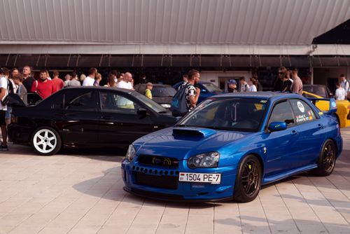 Free A vibrant car show featuring a blue Subaru Impreza and black Mitsubishi Lancer. Stock Photo