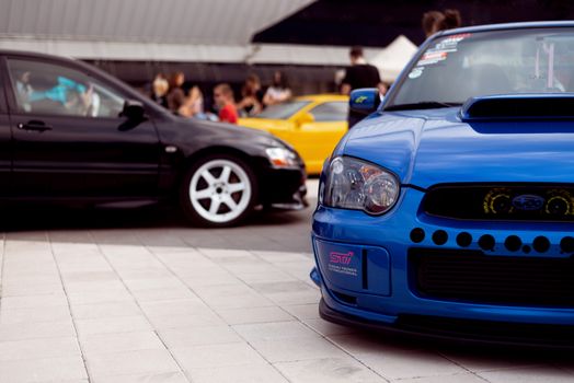 Vibrant sports cars showcased at a lively outdoor automotive event.