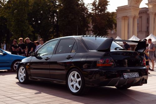 Free A stylish black Mitsubishi Lancer with spoiler showcased at an outdoor urban car event. Stock Photo