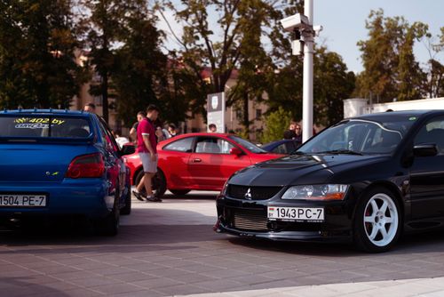 Free A bustling car meet showcasing black and blue sports cars in an urban setting. Stock Photo