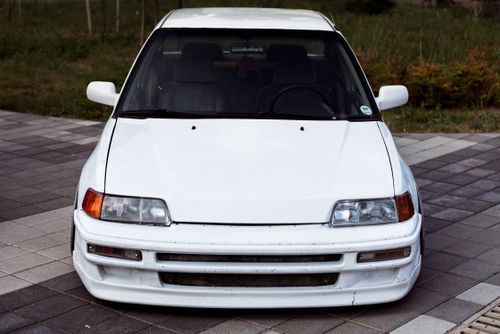 Free Front view of a white Honda Civic parked on a city pavement, showcasing sleek design. Stock Photo