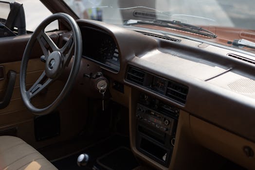 Close-up view of a vintage car interior showcasing the dashboard and steering wheel.