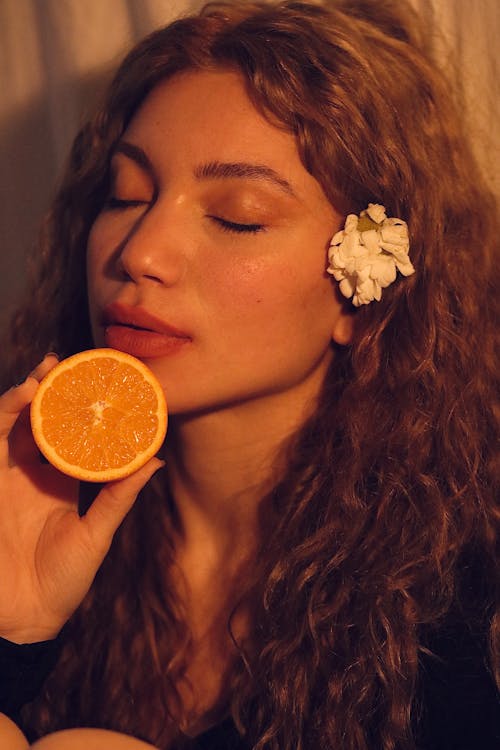 Woman Posing with Orange Slice and Flower in Hair