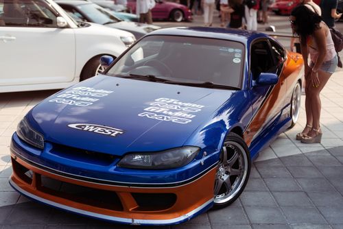 Free A blue and orange Nissan Silvia displayed at an urban car show, attracting onlookers. Stock Photo