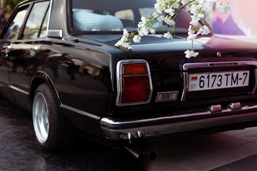 A classic black Toyota car with white blossoms hanging, creating a vintage and elegant scene.